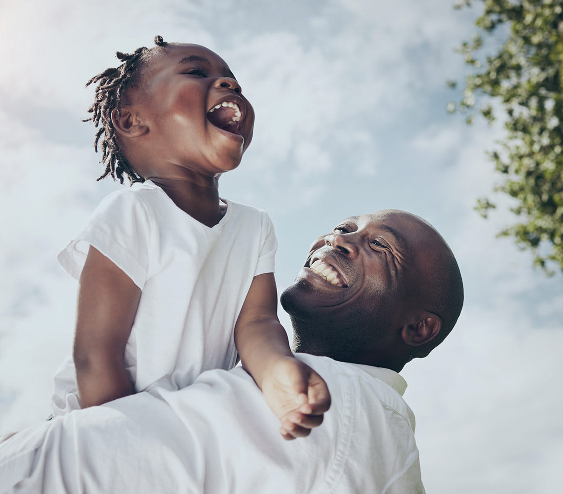 Image of a man holding up a child in mid-air, laughing.